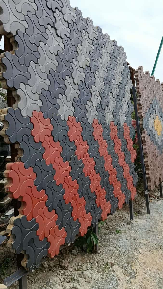Cross-shaped cabro blocks in grey, charcoal and red diagonal bands on a display panel in the yard