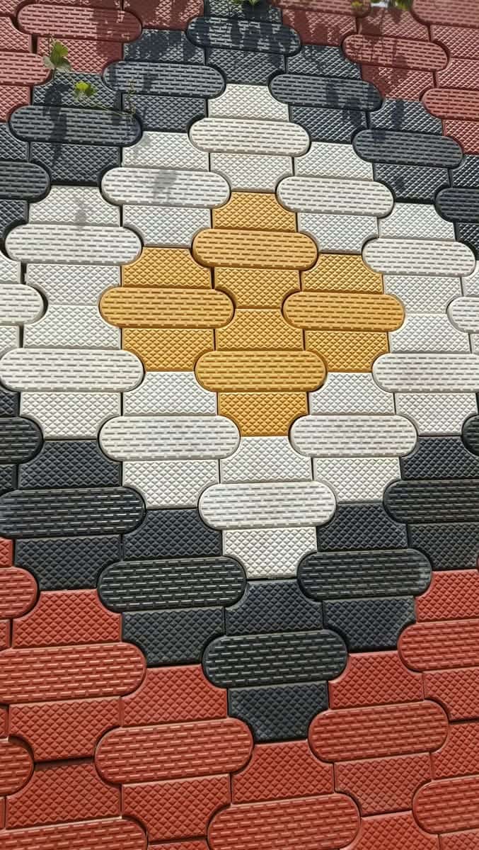 Oval soft-grip cabro in white, yellow, charcoal and red forming a diamond motif, close-up on a yard display panel