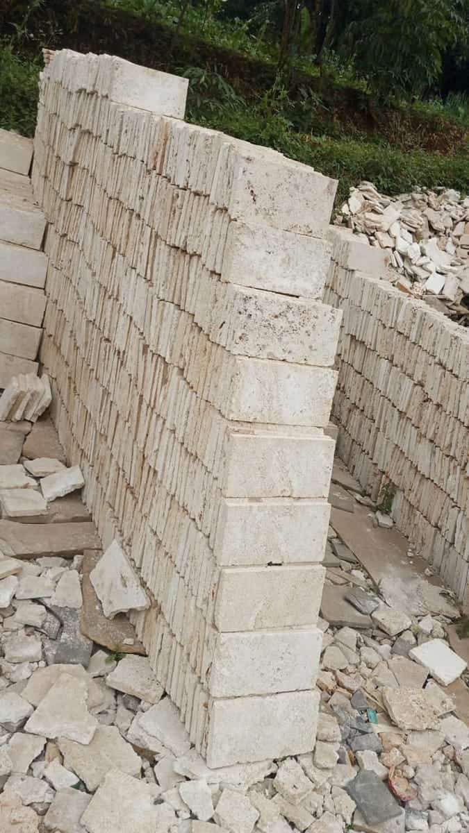 Cut coral stone blocks stacked in courses at the quarry, showing the cream colour and rough texture