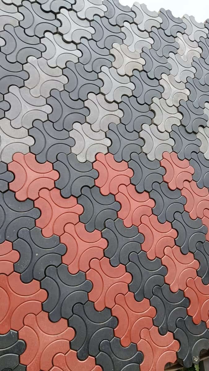 Close-up of grey, red and charcoal cross-shaped cabro showing the four-lobe interlock